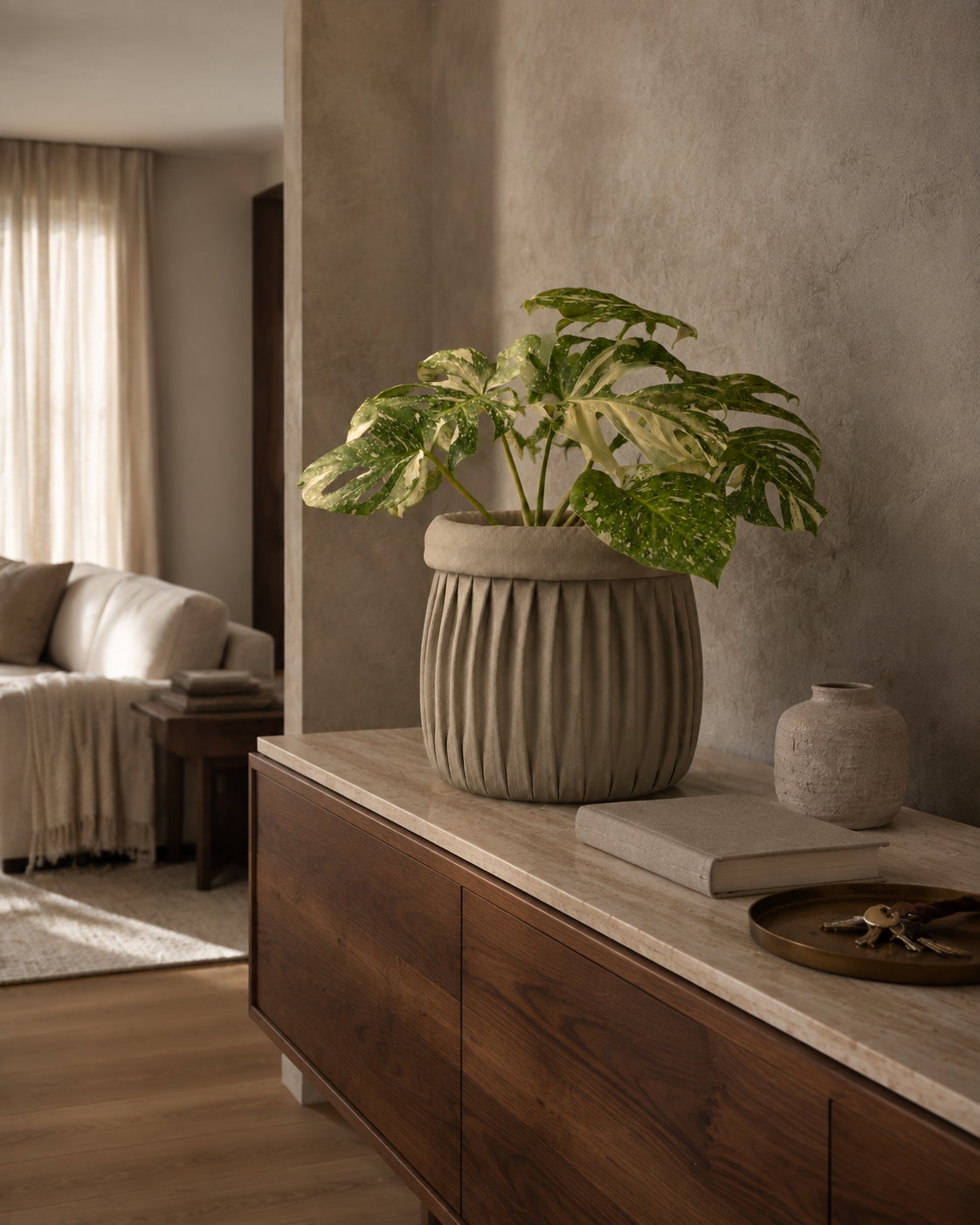 A softly pleated neutral linen planter cover in a calm living room